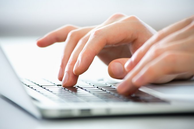 Netzanschlussportal im Online Service Zwei Hände tippen etwas auf den silbernen Laptop.