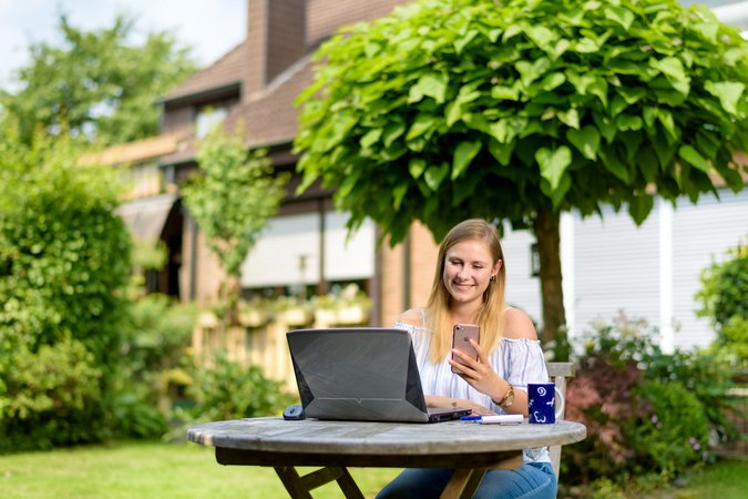 Eine Frau sitzt am Laptop und befindet sich im Garten