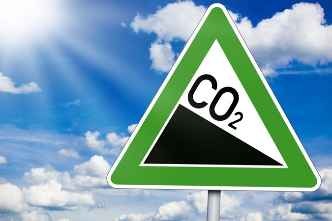 Ein CO2 Zeichen als Verkehrszeichen dargestellt. Im Hintergrund ein strahlender Himmel.
