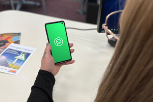Aufnahme auf ein Handy mit WhatsApp Logo aus der User Perspektive. Im Hintergrund ein runder Tisch.
