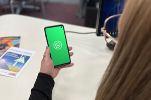 Aufnahme auf ein Handy mit WhatsApp Logo aus der User Perspektive. Im Hintergrund ein runder Tisch.