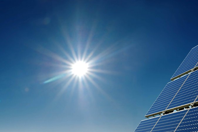 Die Sonne in der Mitte des Bildes strahlt auf einige Solar Panels in der Rechten Ecke des Bildes.