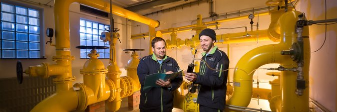 Zwei Männer stehen in einer Übergabestation einer großen Wasserpumpe 