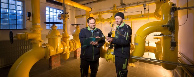 Zwei Männer stehen in einer Übergabestation einer großen Wasserpumpe 