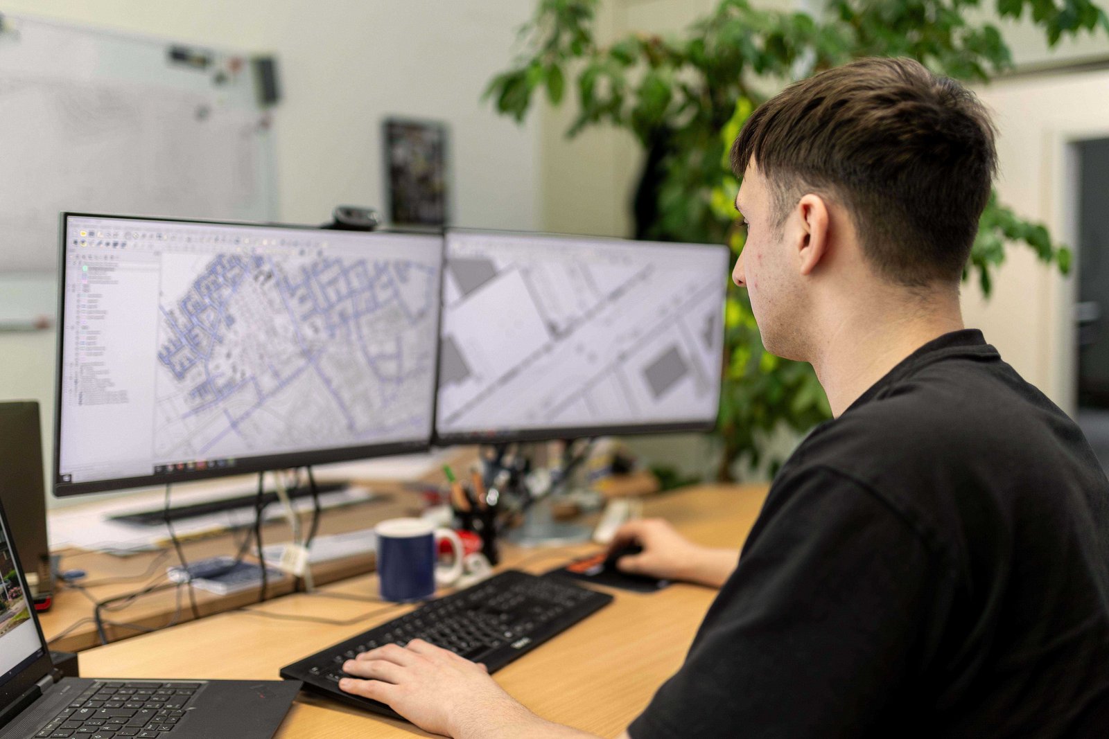 Junger Mann vor Computerbildschirmen sitzend
