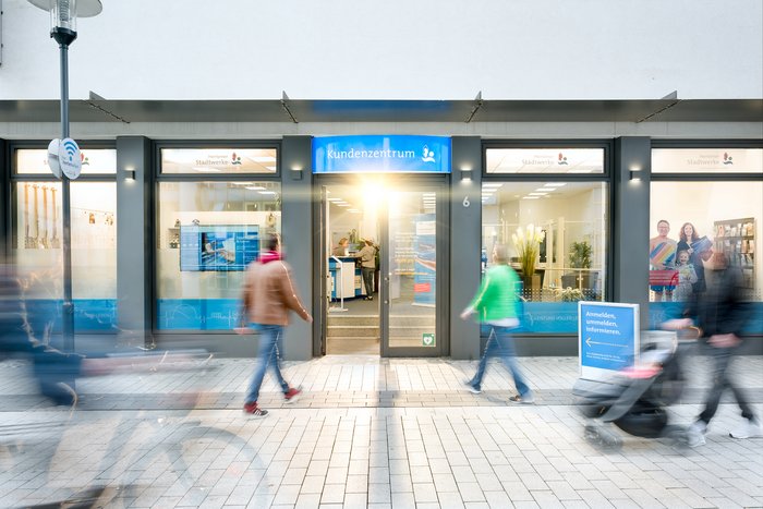 Eingangsbereich in grau und blau, in den 3 Menschen hineintreten