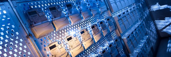 Die Hardware eines Messstellenbetriebs, mehrere Messgeräte hängen an einer blau leuchtenden Wand