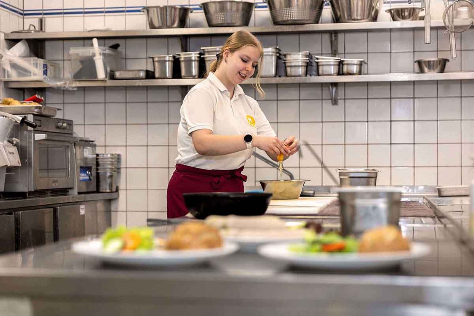 Junge Frau in Großküche beim Anrichten von Speisen
