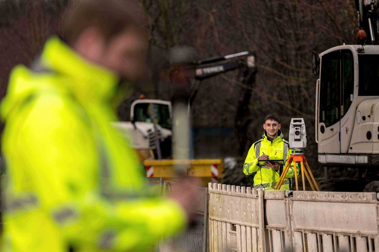 Zwei junge Männer auf einer Baustelle mit Vermessungsutensilien