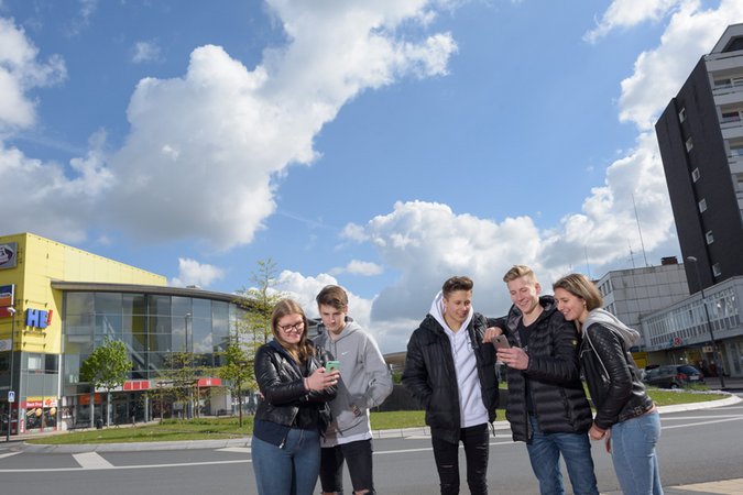 2 Gruppen von Personen, die auf ihr Smartphone schauen vor einem Bürogebäude