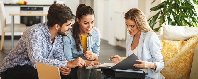 Drei Menschen sitzen an einem Tisch und schauen in eine Broschüre.