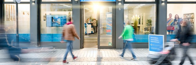 Mehrere Menschen laufen in Richtung eines Kundenzentrums