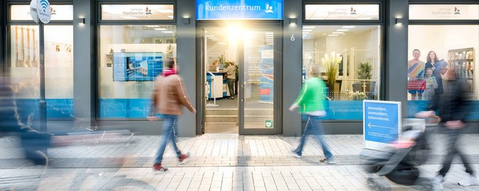 Mehrere Menschen laufen in Richtung eines Kundenzentrums