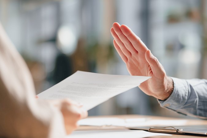 Ein schriftlicher Vertrag wird durch eine Hand abgelehnt beziehungsweise widerrufen.