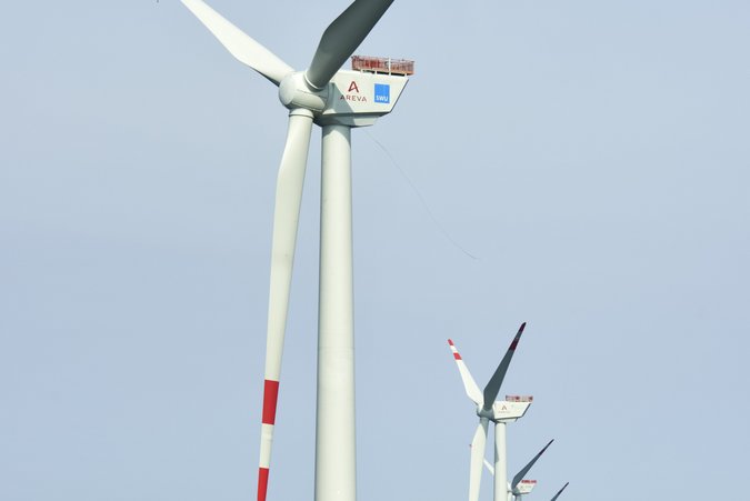 AREVA Windkraftanlage weißes Windrad, dessen unterer Teil gelb ist mit rot weißen Flügel im Meer freistehend