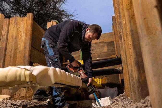Techniker beim Arbeiten an einer Versorgungsleitung in einer Baugrube