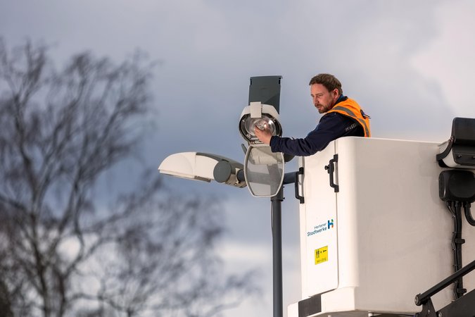 Techniker beim Arbeiten an einer Straßenlaterne in einem Hubsteiger